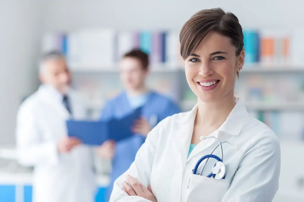 In a close-up shot, a female doctor smiles at the camera