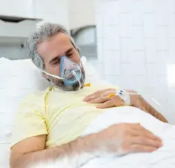 man lying on hospital bed with oxygen mask