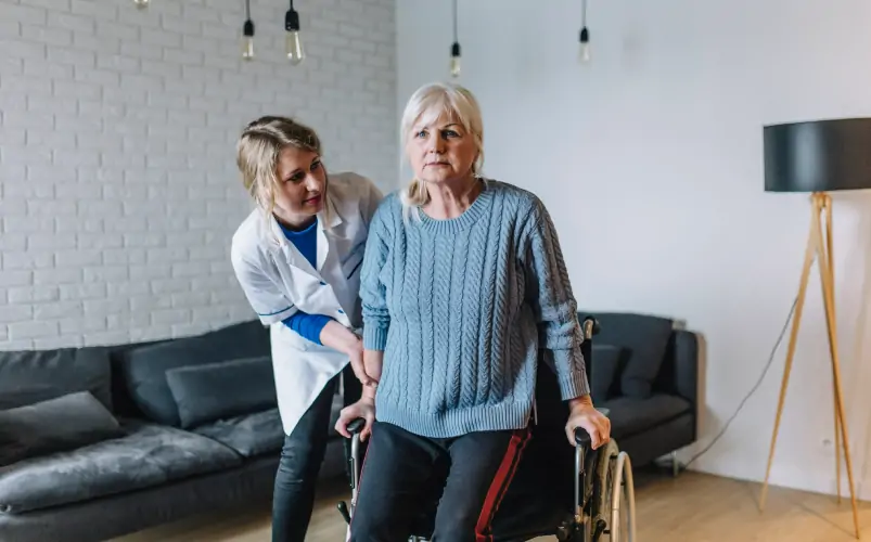 female doctor in white uniform visiting disabled elderly adult patient at home