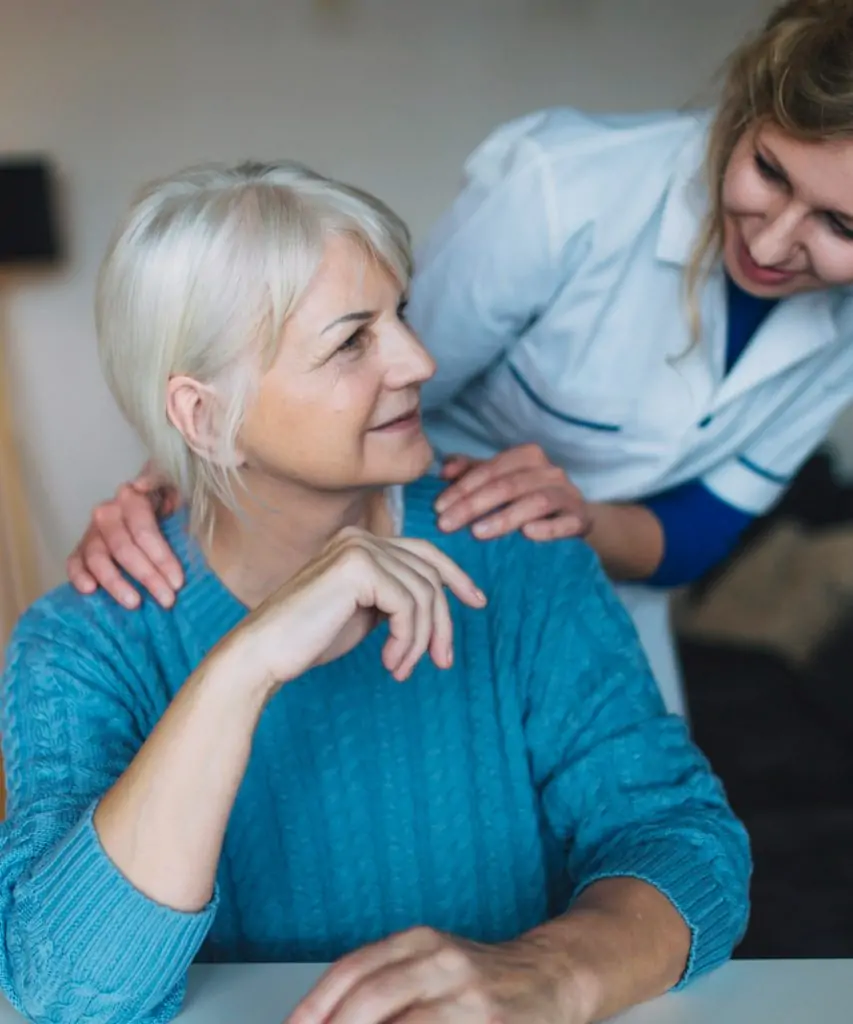 Smiling young female doctor standing behind old woman